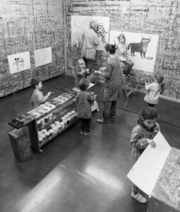 Groupe d'enfants et un adulte en train de peindre, photo en noir et blanc.