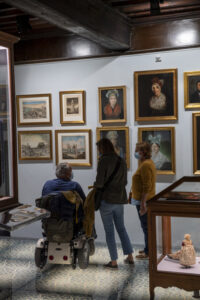 Groupe de visiteurs, dont une personne en fauteuil roulant, en train d'admirer les collections du musée