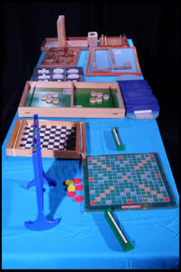 Table couverte de jeux de plateau, notamment scrabble, dominos et échiquier.